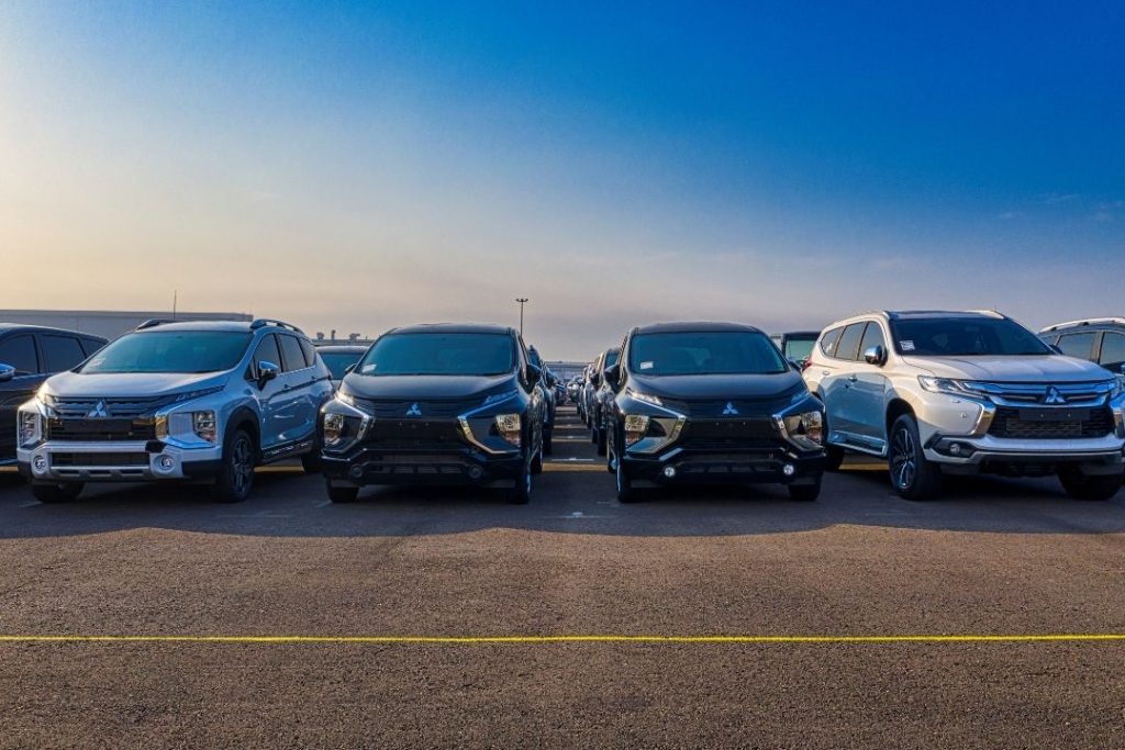 Four Mitsubishi SUVs, often used in mining and civil mechanical services, are parked side by side in a lot under a clear blue sky, with other vehicles visible in the background. The vehicles are arranged in a row facing forward.
